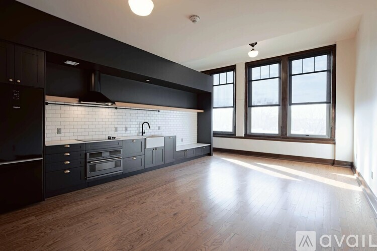 A kitchen with black cabinets and a wooden floor.