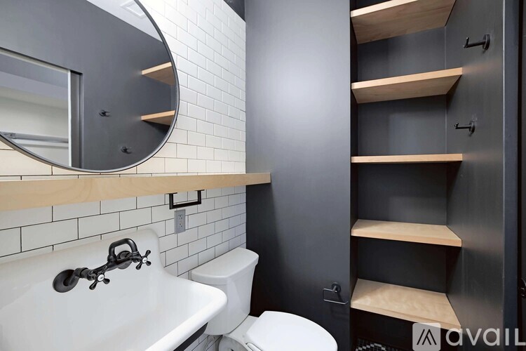 A bathroom with a white sink, toilet, and a mirror above a shelf.