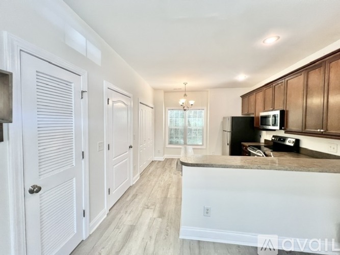 A kitchen with white cabinets and a black refrigerator.