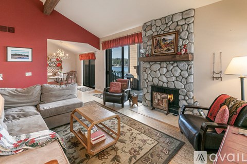 A living room with a stone fireplace and a grey sofa.