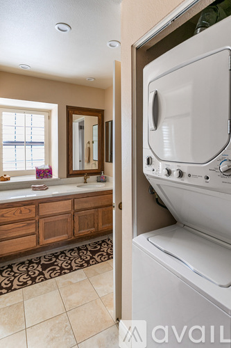A white dryer is in a small space next to a window.