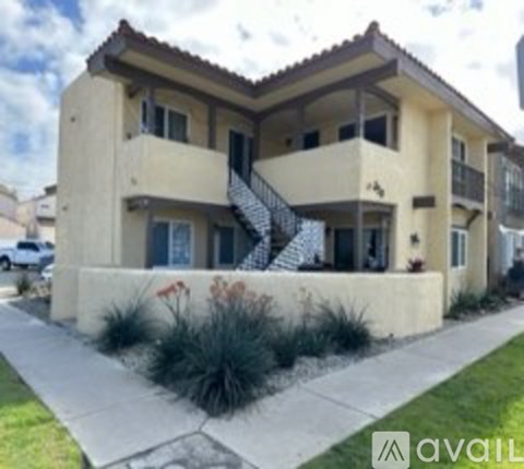 A two-story beige house with a balcony and a staircase.