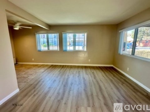 Empty room with wooden flooring and three windows.