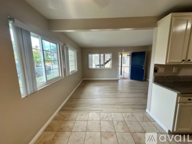 A spacious room with tiled flooring and large windows.