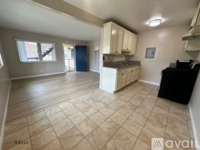 A kitchen area with a black fridge and white cabinets.