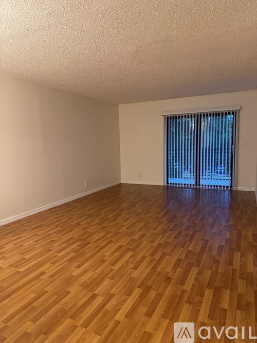 A room with wooden flooring and a window with blinds.