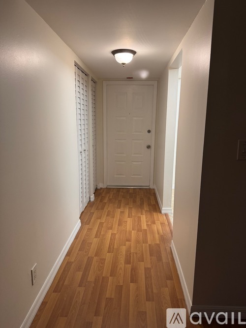 A hallway with wooden floors and a white door.