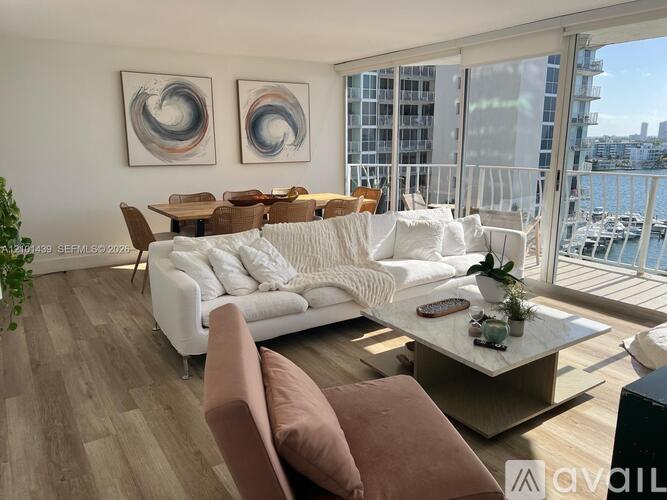 A living room with a white couch and brown pillows.