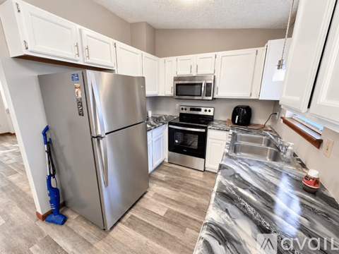 A kitchen with a stainless steel refrigerator and a marble countertop.