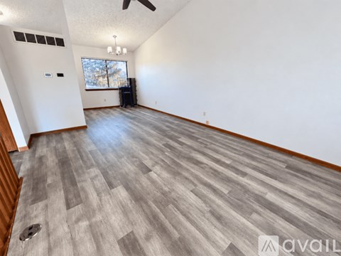 A spacious room with a grey wood floor and a ceiling fan.