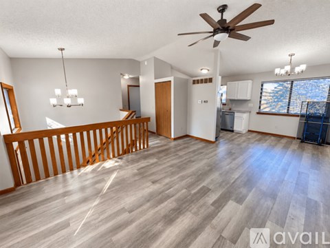 A spacious living room with a ceiling fan and hardwood flooring.