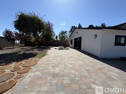 A sunny day with a white building and a brick pathway.