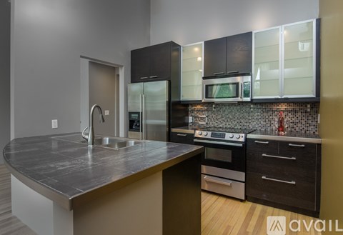 A modern kitchen with a stainless steel countertop and black appliances.