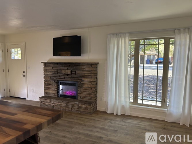 A living room with a stone fireplace and a flat screen TV mounted above it.