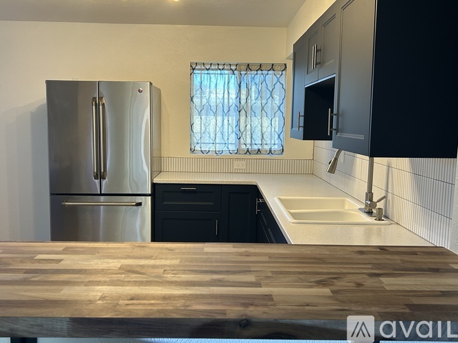 A kitchen with a stainless steel refrigerator and wooden countertops.