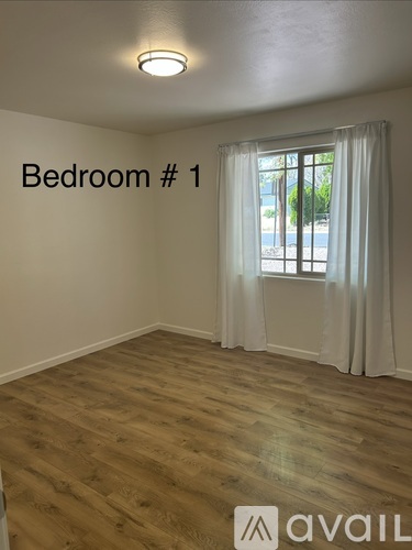 Bedroom 1 has a window with white curtains and wooden flooring.