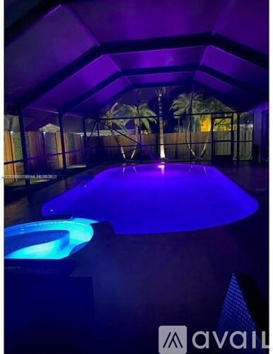 A hot tub in a room with purple lighting.