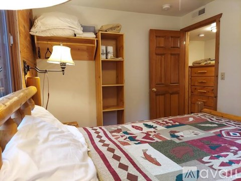 A bedroom with a bed, a lamp, and a wooden door.