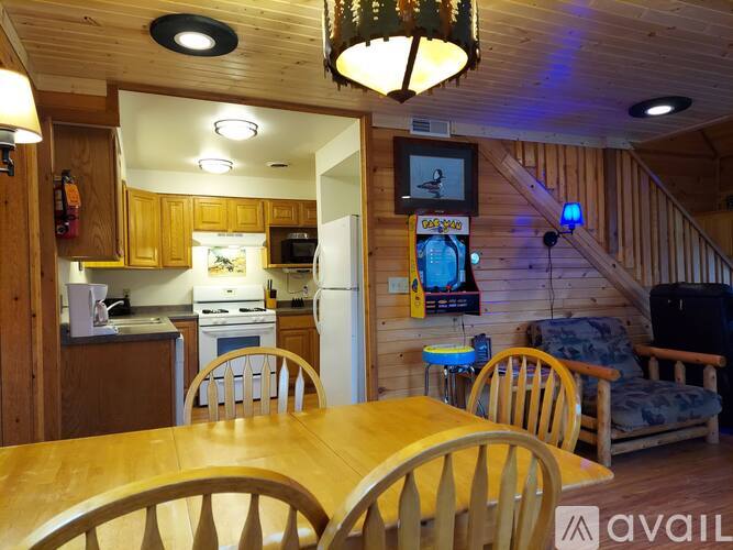 A wooden table is surrounded by chairs in a kitchen area.