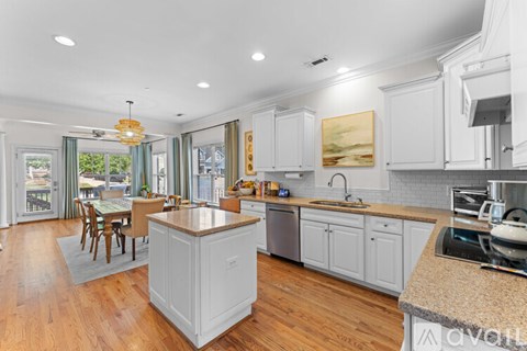 A kitchen with white cabinets and a wooden island.
