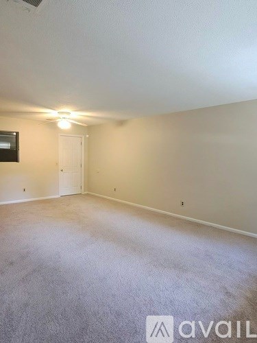 A room with a carpeted floor and a ceiling fan.