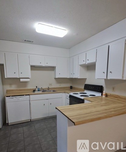 A kitchen with white cabinets and a wooden counter.