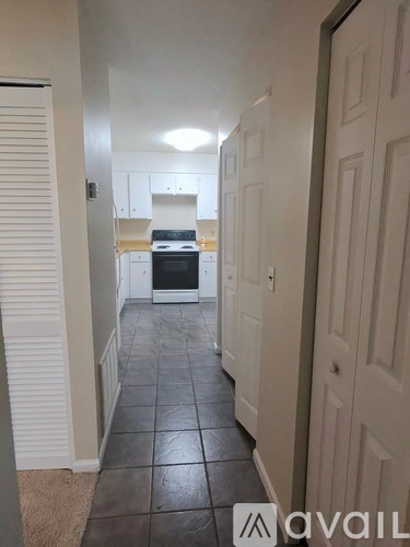 A hallway with a kitchen visible in the background.
