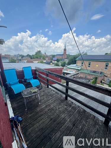 A balcony with two chairs and a table overlooking a cityscape.