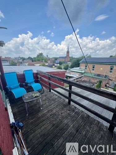 A balcony with two chairs and a table overlooking a cityscape.