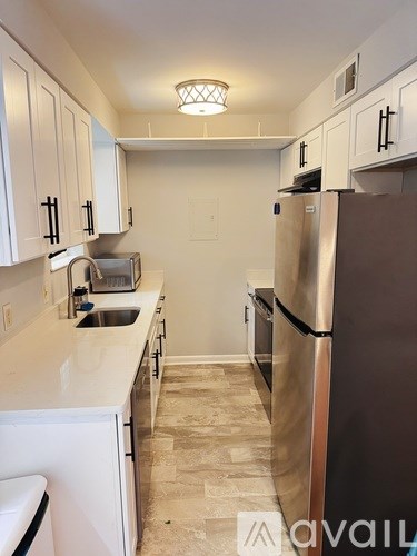 A kitchen with white cabinets and a refrigerator.