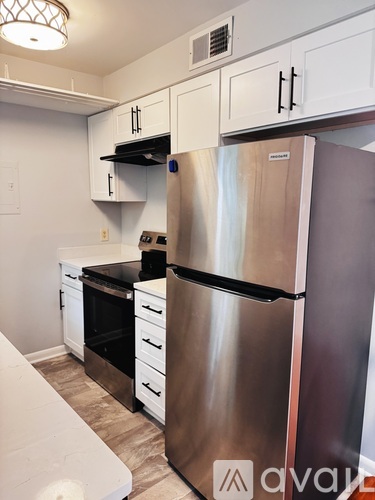 A kitchen with a stainless steel refrigerator and white cabinets.