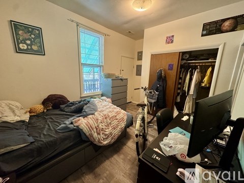 A bedroom with a bed, a desk, and a bicycle.