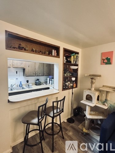 A kitchen area with a sink, two chairs, and a cat tree.