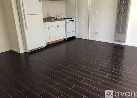A kitchen with white appliances and cabinets, and a black tile floor.