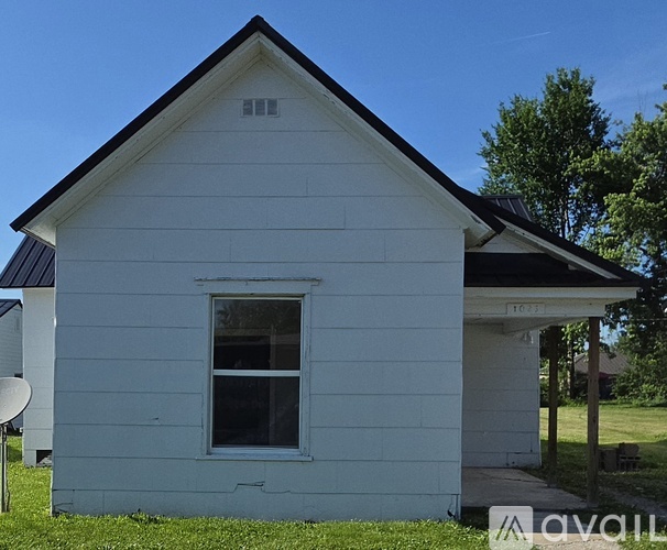 A small white house with a black roof and a window.