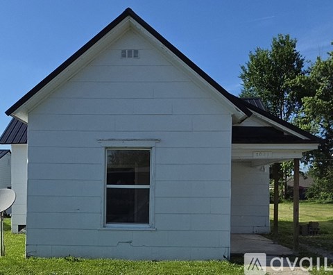 A small white house with a black roof and a window.