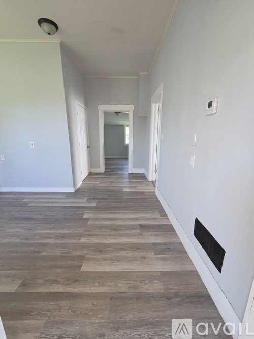 A long hallway with wood floors and white walls.