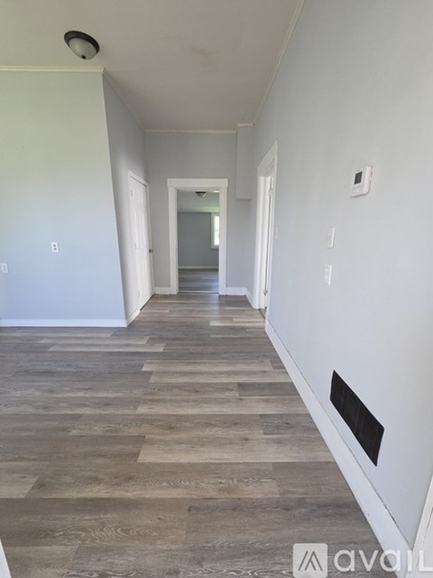 A long hallway with wood floors and white walls.