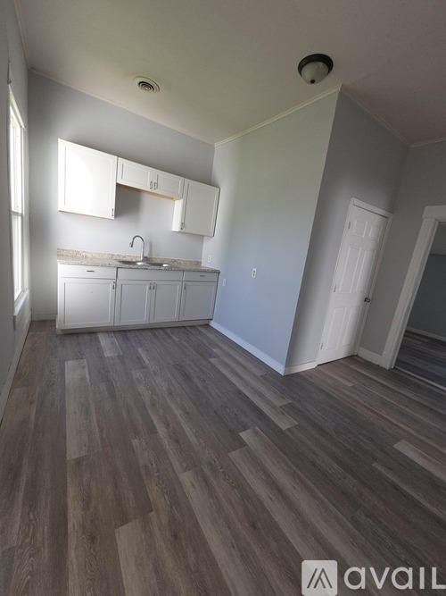 A kitchen with white cabinets and a wooden floor.