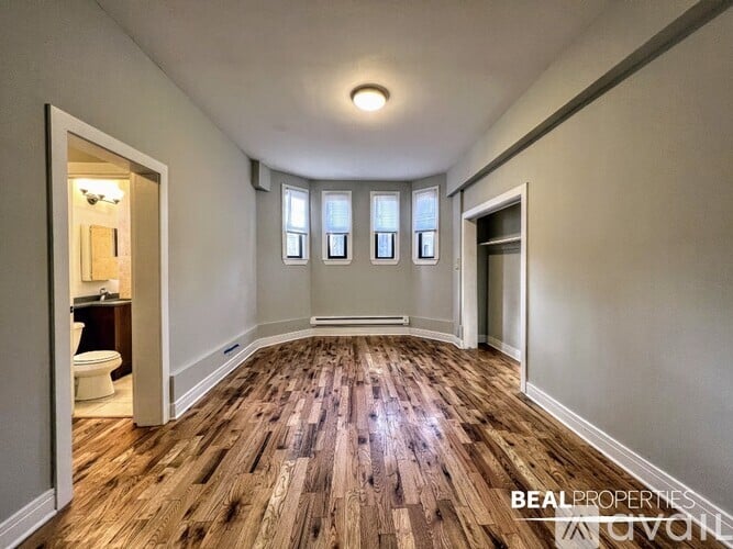A spacious room with wooden flooring and a large mirror on the wall.