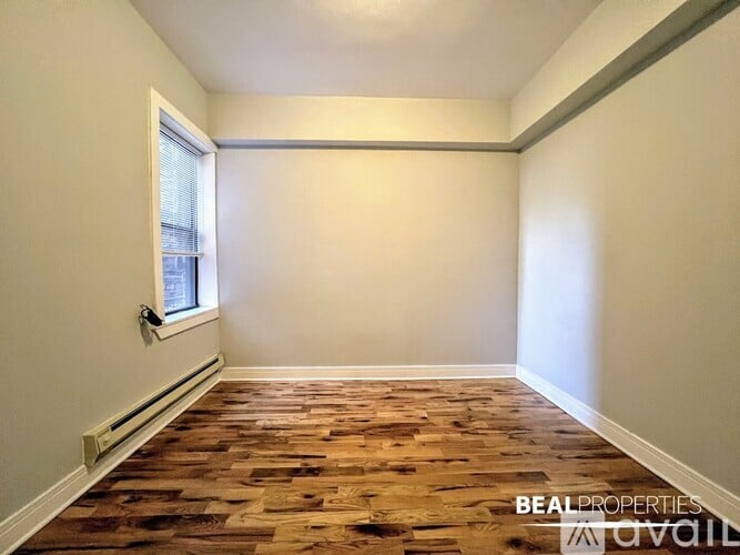 A room with wooden flooring and a window on the left side.