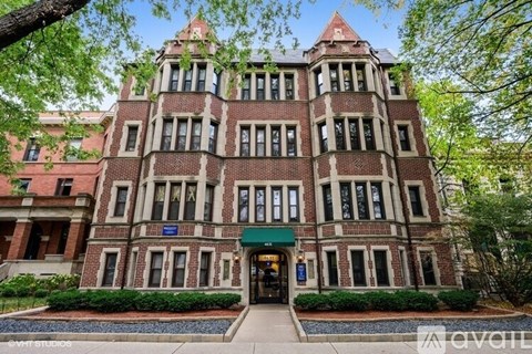 A large, red brick building with a green awning and a sign that says "available" in front of it.