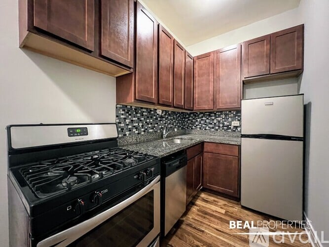 A kitchen with a black stove top oven and wooden cabinets.