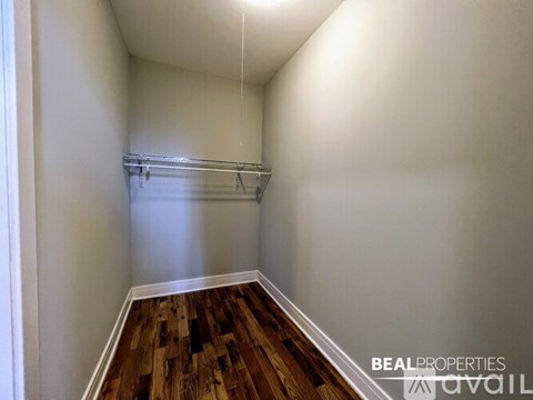 A room with wooden floors and white walls, with a white ceiling and a white baseboard.