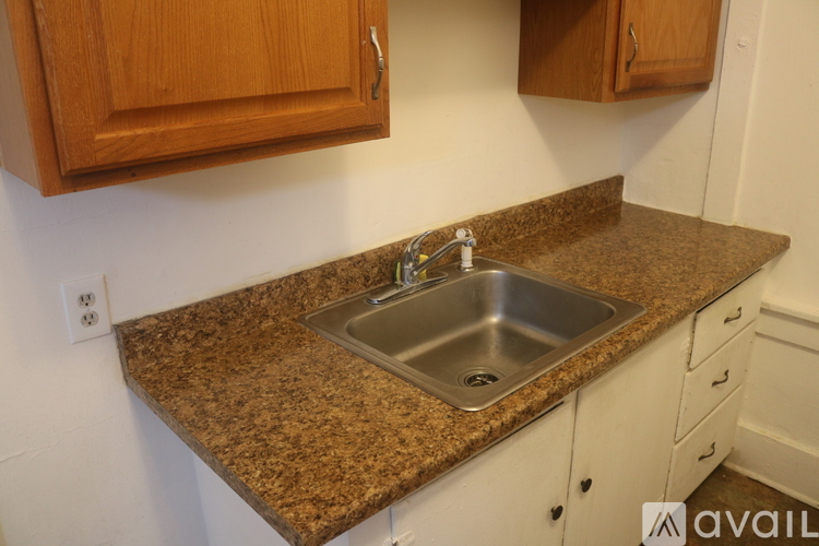 A kitchen counter with a sink and wooden cabinets.
