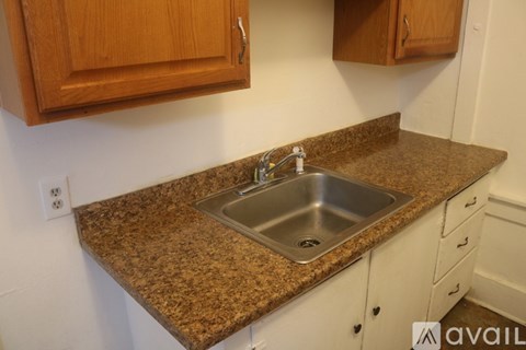A kitchen counter with a sink and wooden cabinets.