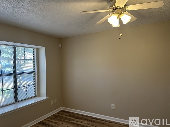A room with a ceiling fan and a window with blinds.