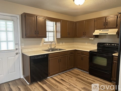 A kitchen with wooden cabinets and a black dishwasher.