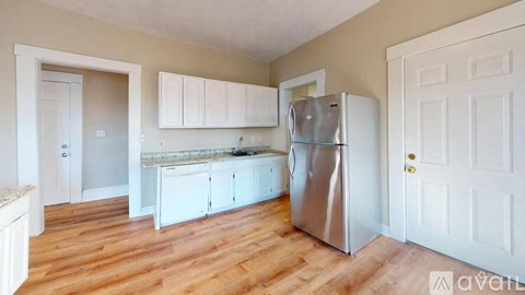 A kitchen with a refrigerator, cabinets, and a countertop.