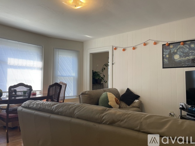 A living room with a couch, chairs, and a television.